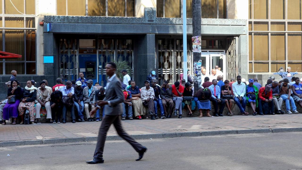 Kontoinhaber sitzen vor einer Filiale der Barclasy Bank in Harare (Simbabwe) um Bargeld abzuheben Kontoinhaber sitzen vor einer Filiale der Barclasy Bank in Harare (Simbabwe) um Bargeld abzuheben