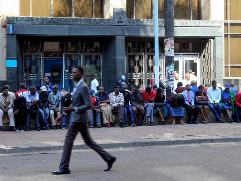Kontoinhaber sitzen vor einer Filiale der Barclasy Bank in Harare (Simbabwe) um Bargeld abzuheben