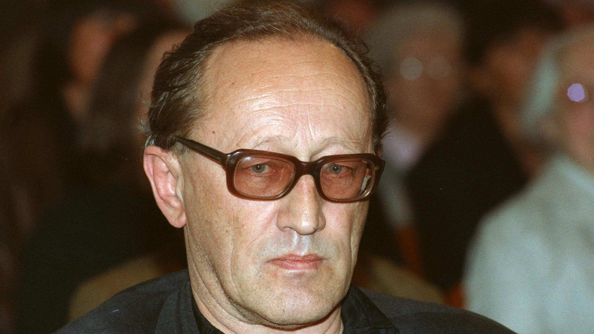 Heiner Müller trägt eine Brille mit rot-getönten Gläsern, er schaut missmutig in die Kamera Heiner Müller trägt eine Brille mit rot-getönten Gläsern, er schaut missmutig in die Kamera