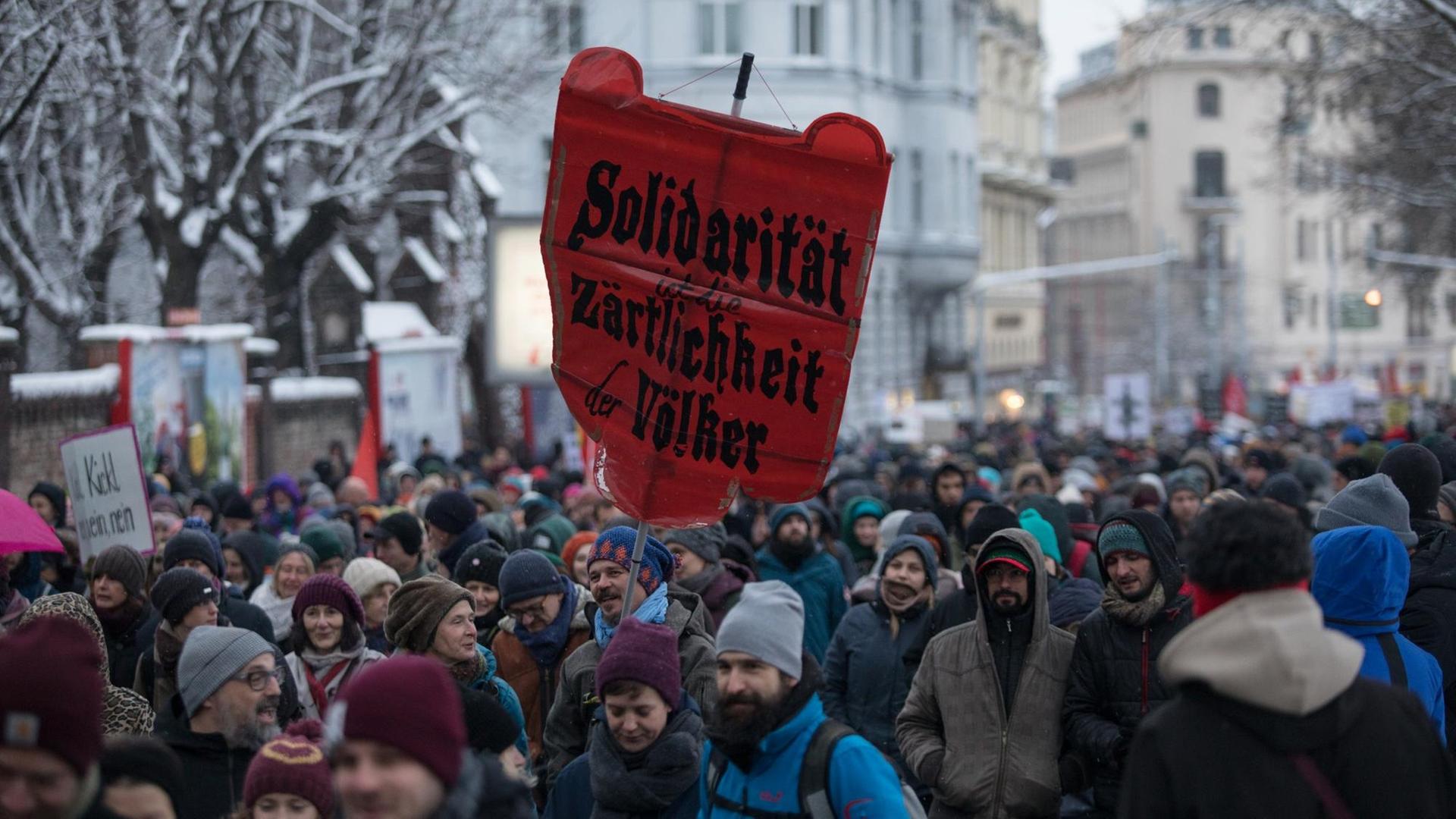 Proteste zum 1. Jahrestag der Regierungsbildung von ÖVP und FPÖ in Wien. Eine Menschenmenge in einem verschneiten Straßenzug, ein Mann hält ein rotes Transparent mit der Aufschrift: "Solidarität ist die Zärtlichkeit der Völker" hoch. Proteste zum 1. Jahrestag der Regierungsbildung von ÖVP und FPÖ in Wien. Eine Menschenmenge in einem verschneiten Straßenzug, ein Mann hält ein rotes Transparent mit der Aufschrift: "Solidarität ist die Zärtlichkeit der Völker" hoch.