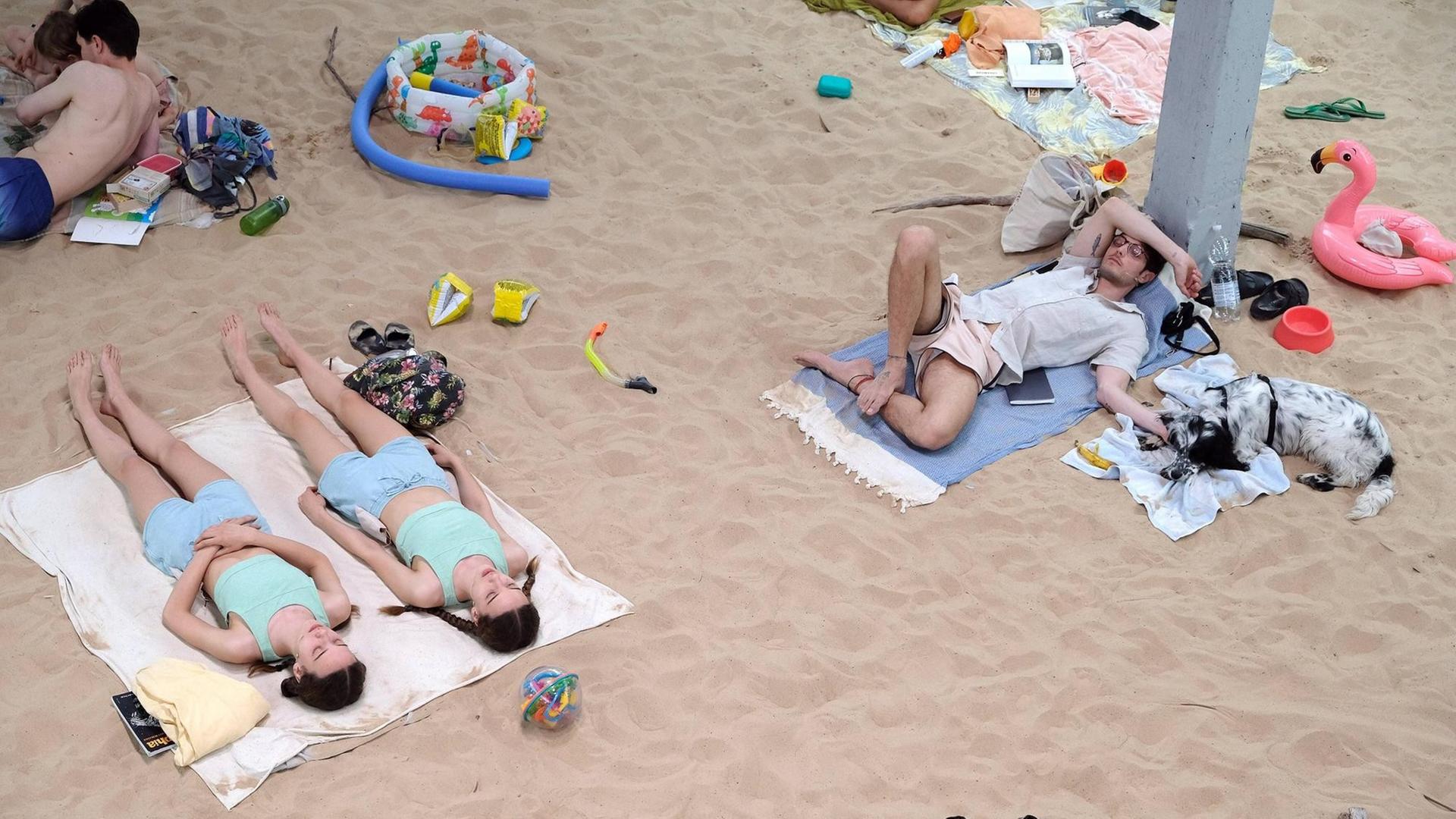 Mehrere Menschen liegen am Strand. Mehrere Menschen liegen am Strand.