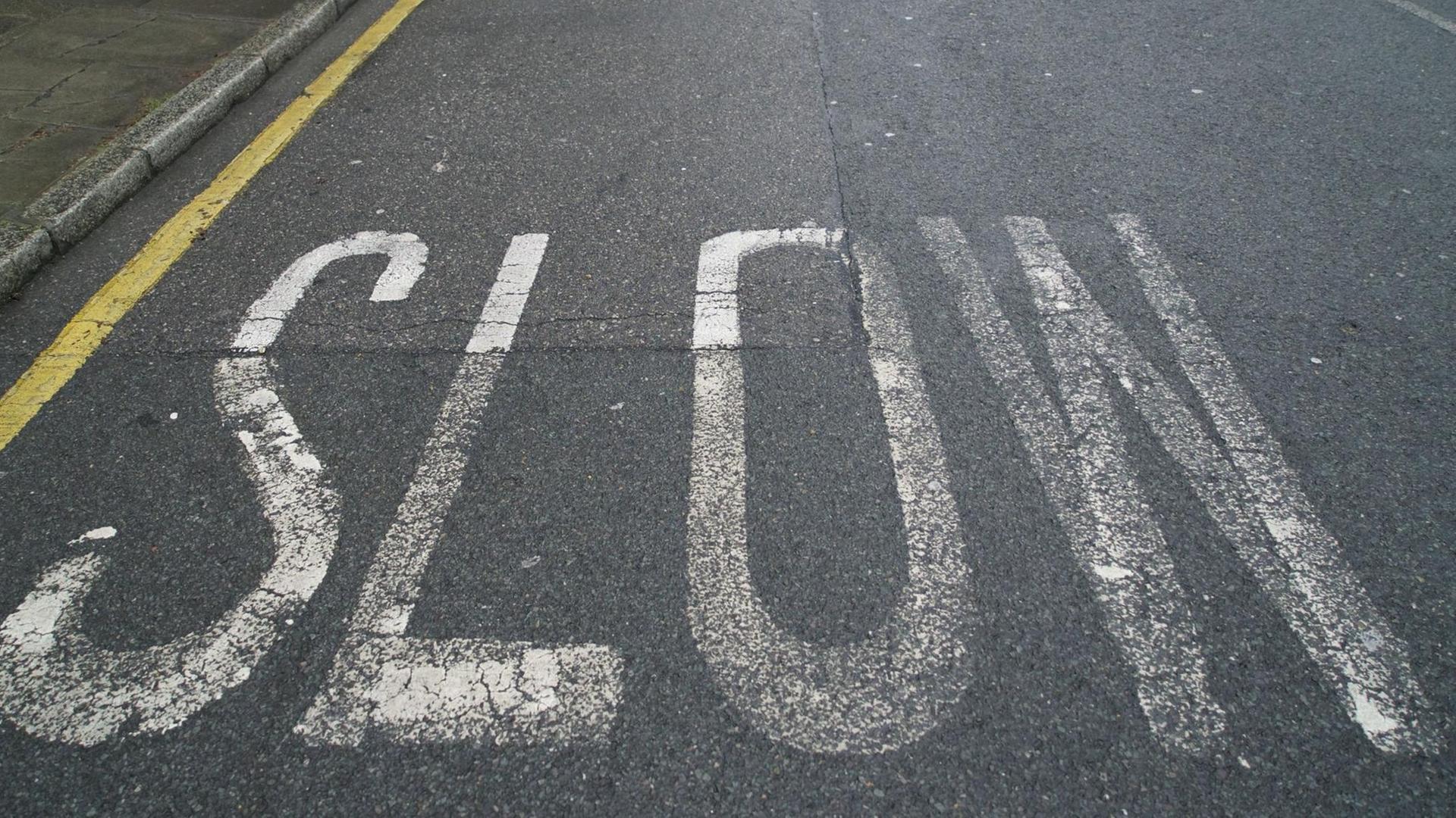 Das Wort "Slow" steht groß auf einer Straße.