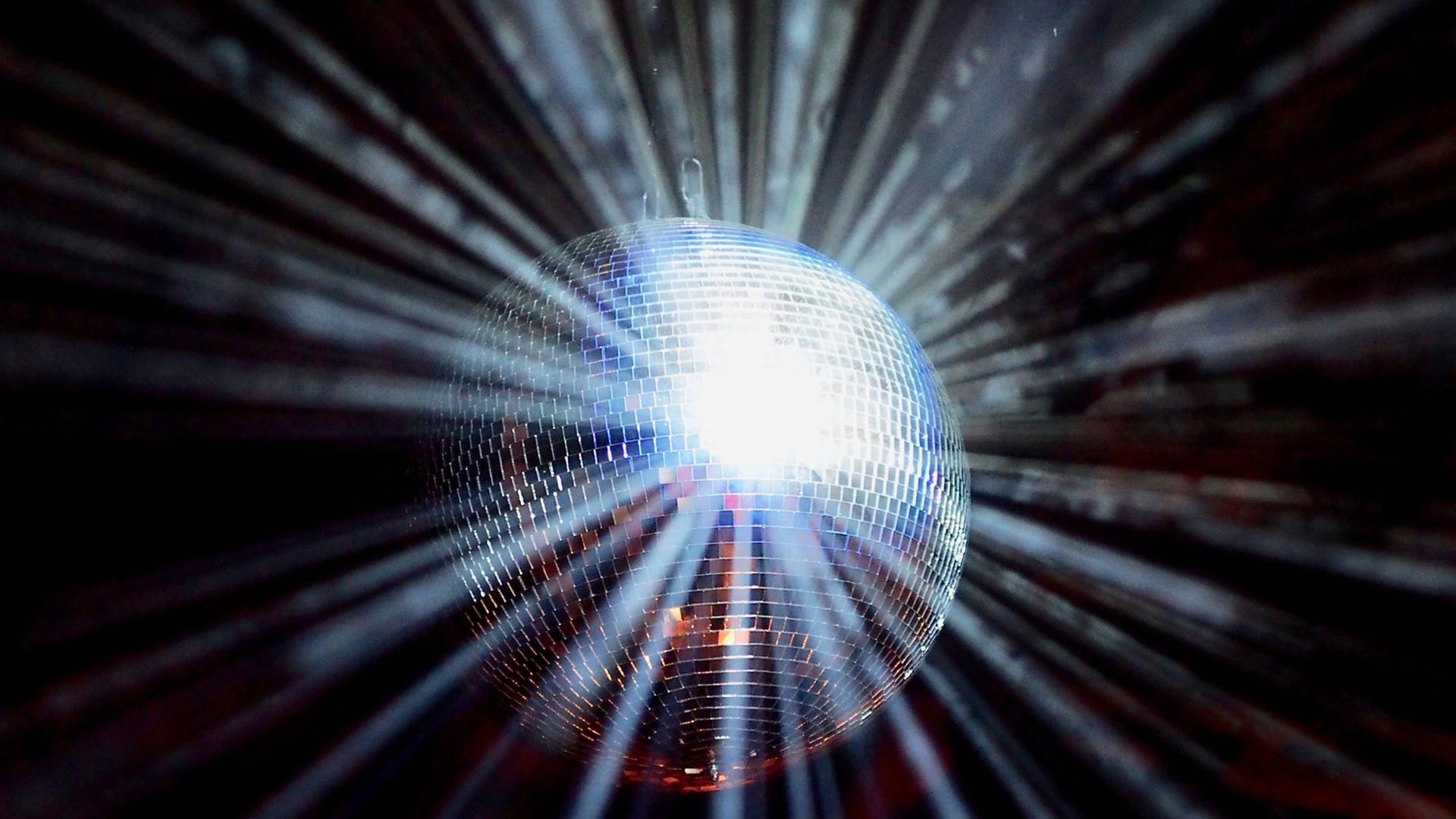 Eine Discokugel wird angestrahlt, das Licht leuchtet sternförmig zurück. Eine Discokugel wird angestrahlt, das Licht leuchtet sternförmig zurück.