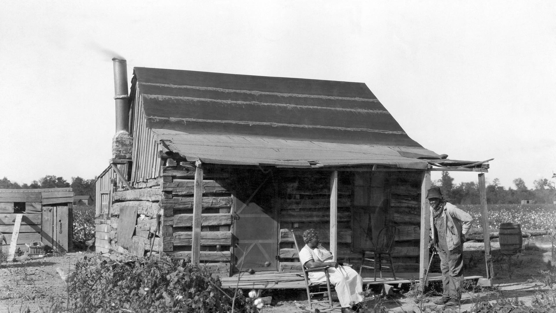 Sklaven im Jahre 1895 vor ihrer Hütte auf einem Baumwollfeld. Sklaven im Jahre 1895 vor ihrer Hütte auf einem Baumwollfeld.