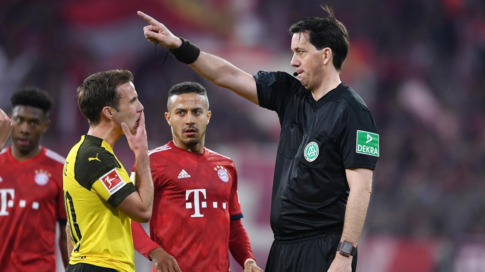 Eine Szene aus dem Bundesliga-Spiel Bayern München gegen Borussia Dortmund. Schiedsrichter Manuel Graefe weist dem Dortmunder Spieler Mario Goetze zurecht. Daneben stehen zwei Fußballer von Bayern München Eine Szene aus dem Bundesliga-Spiel Bayern München gegen Borussia Dortmund. Schiedsrichter Manuel Graefe weist dem Dortmunder Spieler Mario Goetze zurecht. Daneben stehen zwei Fußballer von Bayern München