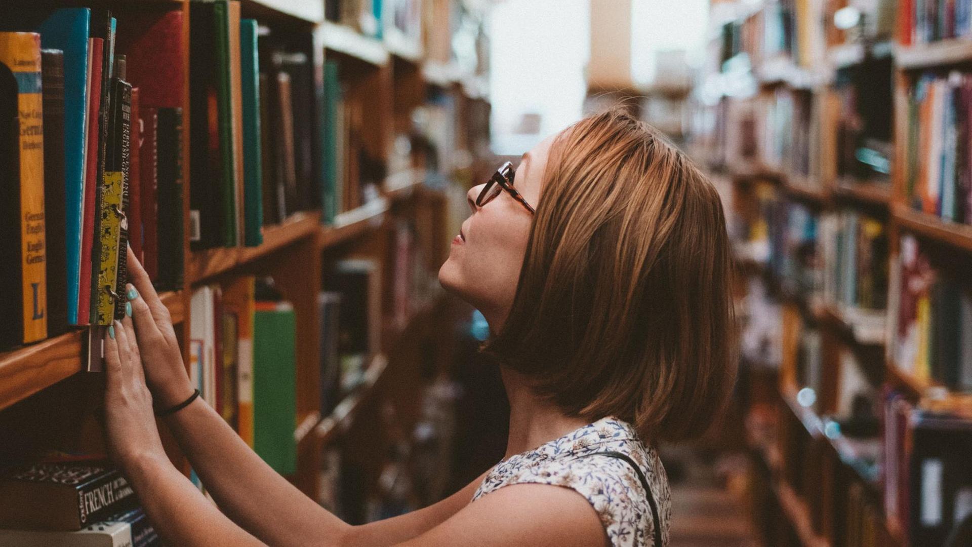 Eine Frau steht vor einem Regal voller Bücher.