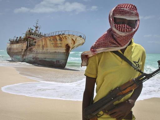 Ein somalischer Pirat steht am Strand vor einem Schiffswrack