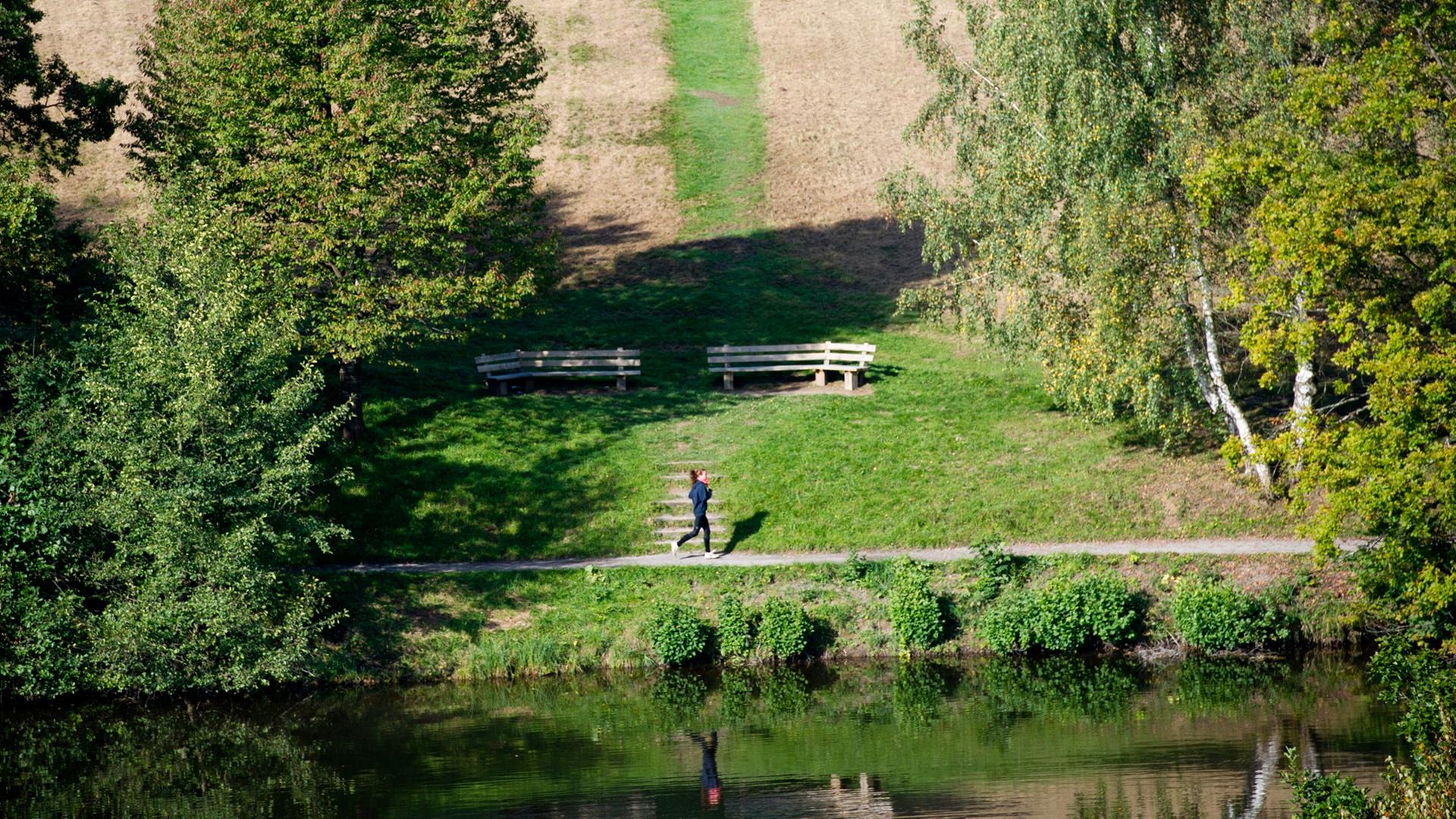 Eine Frau joggt am Bärensee in Stuttgart. Eine Frau joggt am Bärensee in Stuttgart.