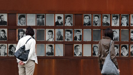 Besucher der Mauergedenkstätte Bernauer Straße sehen sich eine Gedenktafel an, die die Fotos von getöteten DDR-Flüchtlingen zeigt