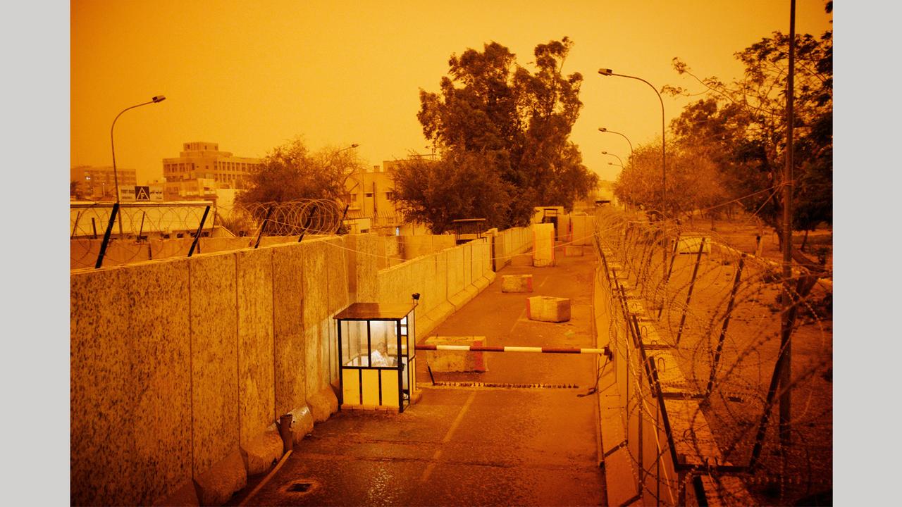 Der mit Betonwänden und Stacheldraht gesicherte Eingang zum Sitz der New York Times in Bagdad während eines Sandsturms 2006: Foto aus dem Bildband "hello camel" von Christoph Bangert über die Absurdität von Krieg Der mit Betonwänden und Stacheldraht gesicherte Eingang zum Sitz der New York Times in Bagdad während eines Sandsturms 2006: Foto aus dem Bildband "hello camel" von Christoph Bangert über die Absurdität von Krieg
