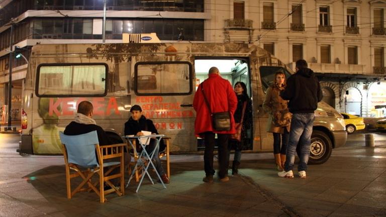Mitarbeiter der Organisation KYTHEA stehen vor einem mobilen medizinischen Versorgungsbus.