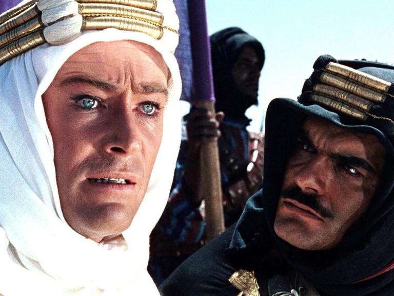 Peter O'Toole blickt bedeutungsschwanger ins Off des Bildes, während Omar Sharif ihn anspricht. Beide tragen Beduinenkleidung.