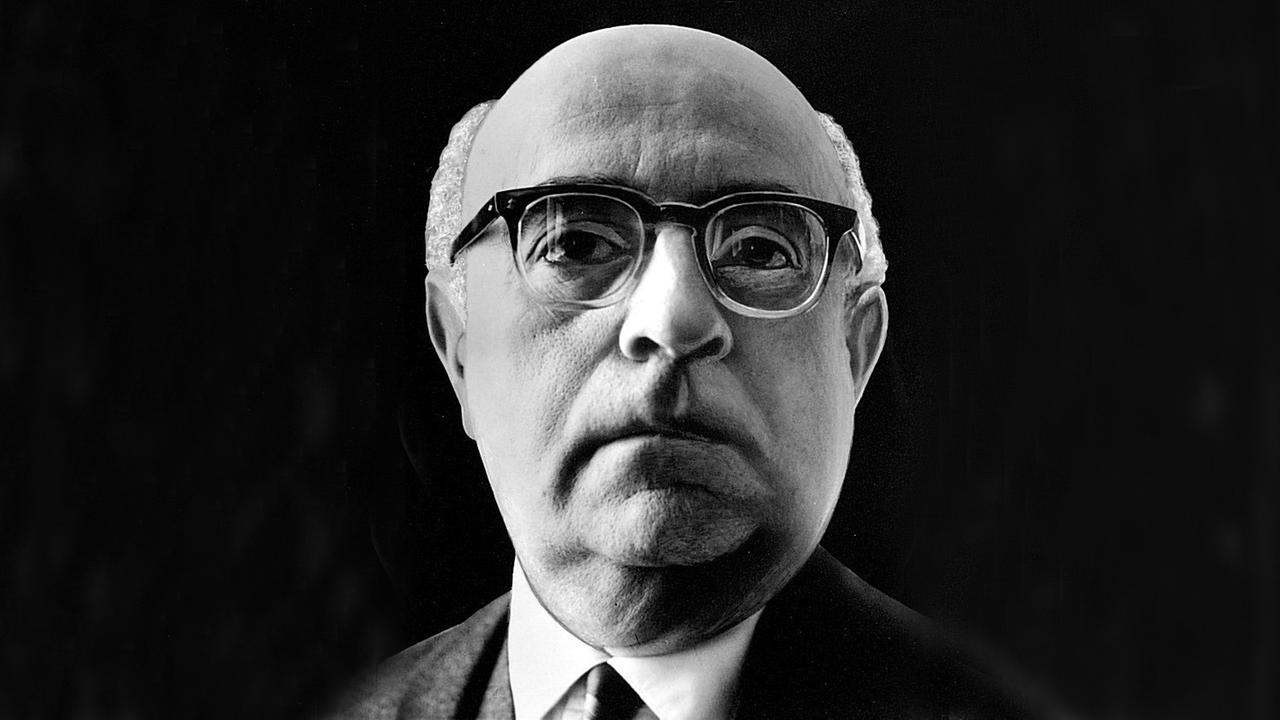 Ein Nahaufnahme von Theodor W. Adorno vor schwarzem Hintergrund. Er trägt eine Hornbrille und schaut aufmerksam dem Betrachter entgegen. Ein Nahaufnahme von Theodor W. Adorno vor schwarzem Hintergrund. Er trägt eine Hornbrille und schaut aufmerksam dem Betrachter entgegen.