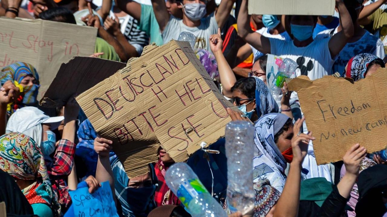 Am 11. September 2020 protestieren Flüchtlinge mit Schildern vor dem ausgebrannten Lager Moria Am 11. September 2020 protestieren Flüchtlinge mit Schildern vor dem ausgebrannten Lager Moria