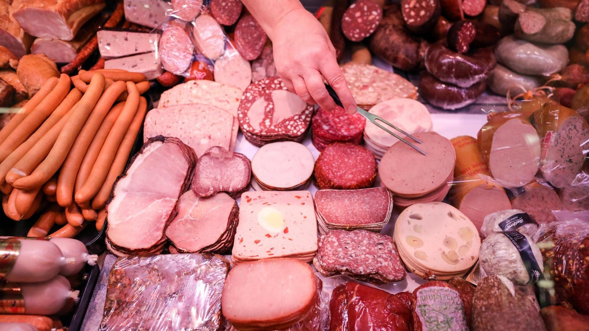 Eine Verkäuferin nimmt Leber-Käse aus einer Fleisch-Theke in einem Supermarkt. Eine Verkäuferin nimmt Leber-Käse aus einer Fleisch-Theke in einem Supermarkt.