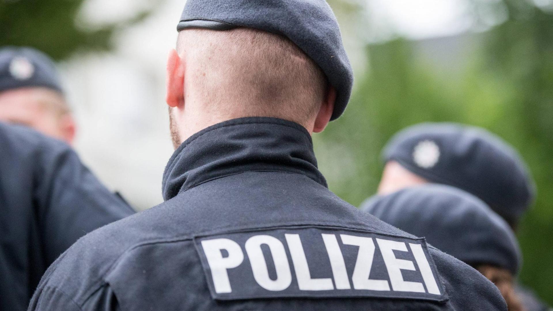 Rückenansicht eines Polizeibeamten. Im Vordergreund ist die Aufschrift "Polizei" zu erkennen. Rückenansicht eines Polizeibeamten. Im Vordergreund ist die Aufschrift "Polizei" zu erkennen.
