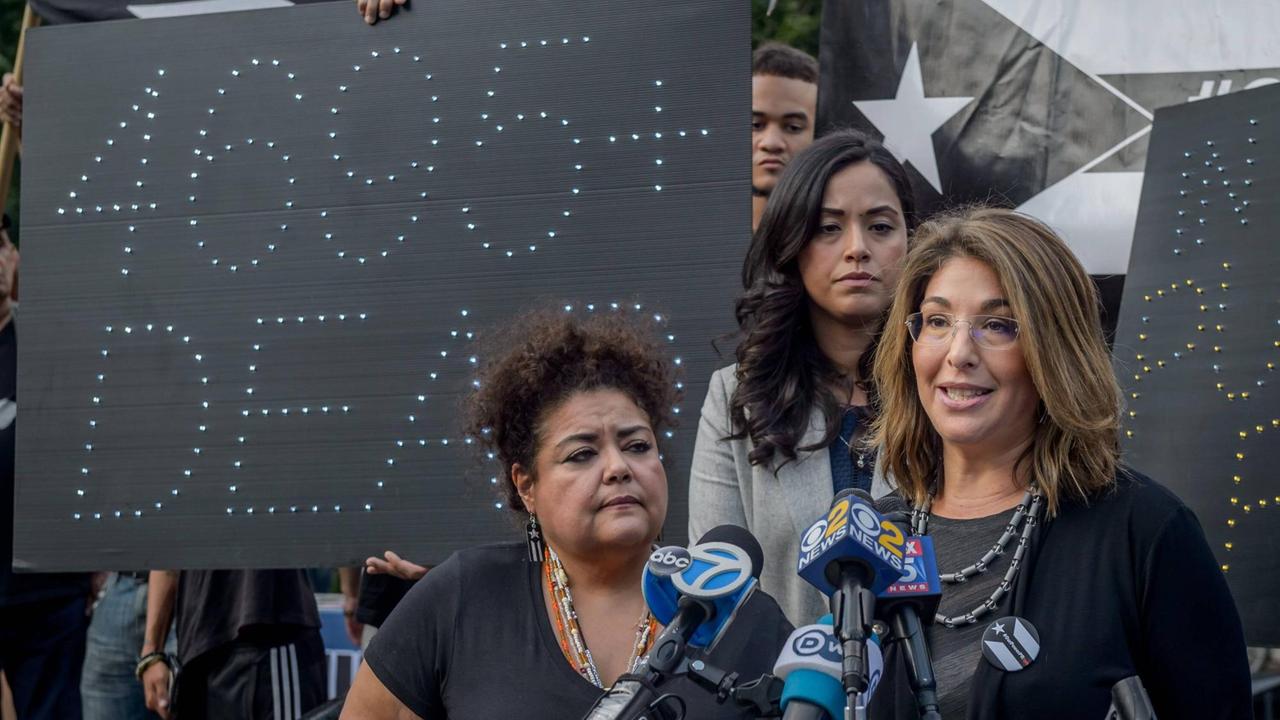 Naomi Klein spricht anlässlich des Jahrestag des Hurricans Maria vor Hunderten Zuhörern. Im Hintergrund wird eine Tafel hochgehalten, auf der steht "4695+ dead", die an die zahlreichen Opfer des Tropensturms erinnert. Naomi Klein spricht anlässlich des Jahrestag des Hurricans Maria vor Hunderten Zuhörern. Im Hintergrund wird eine Tafel hochgehalten, auf der steht "4695+ dead", die an die zahlreichen Opfer des Tropensturms erinnert.