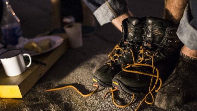 Eine Person hat ihre Wanderschuhe ausgezogen, daneben steht eine Blechtasse Eine Person hat ihre Wanderschuhe ausgezogen, daneben steht eine Blechtasse