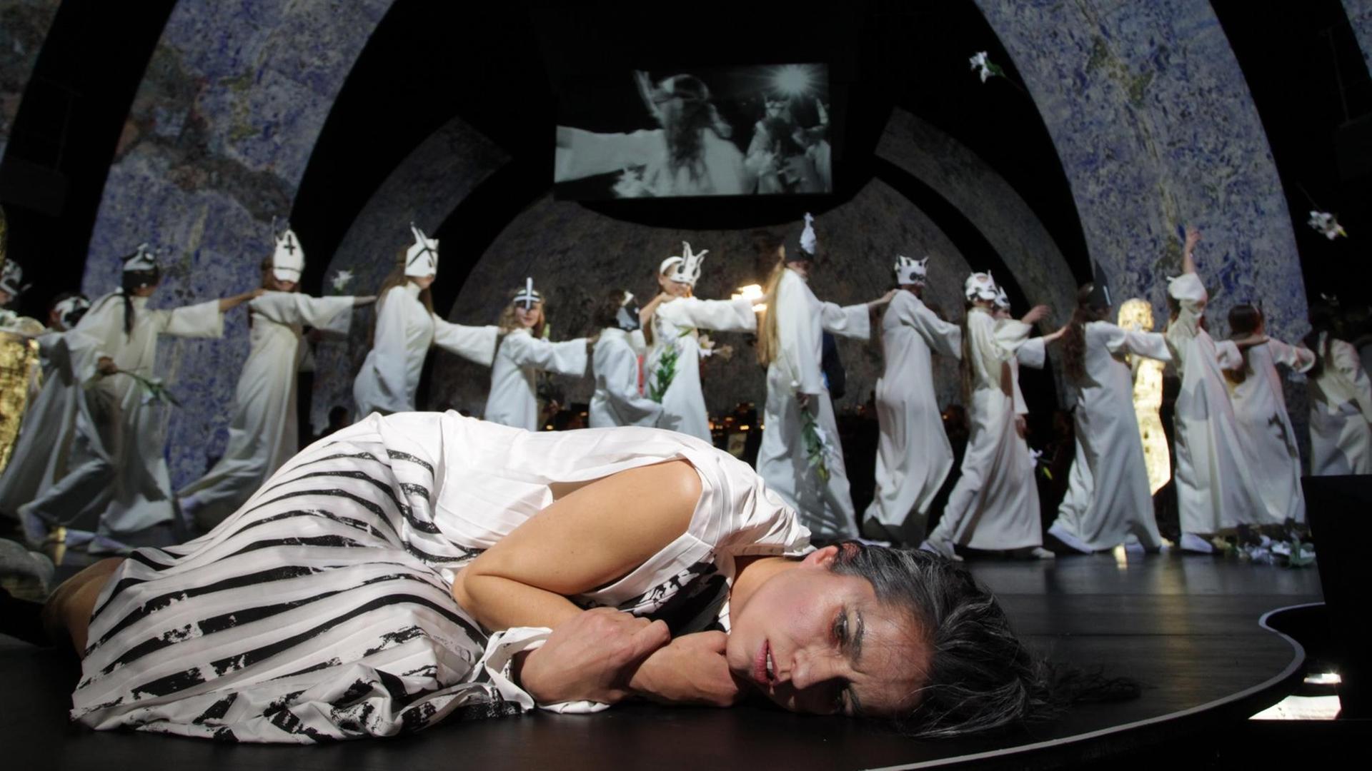 Nadine Lehner liegt auf der Bühne, im Hintergrund der Kinderchor des Theater Bremen. Nadine Lehner liegt auf der Bühne, im Hintergrund der Kinderchor des Theater Bremen.