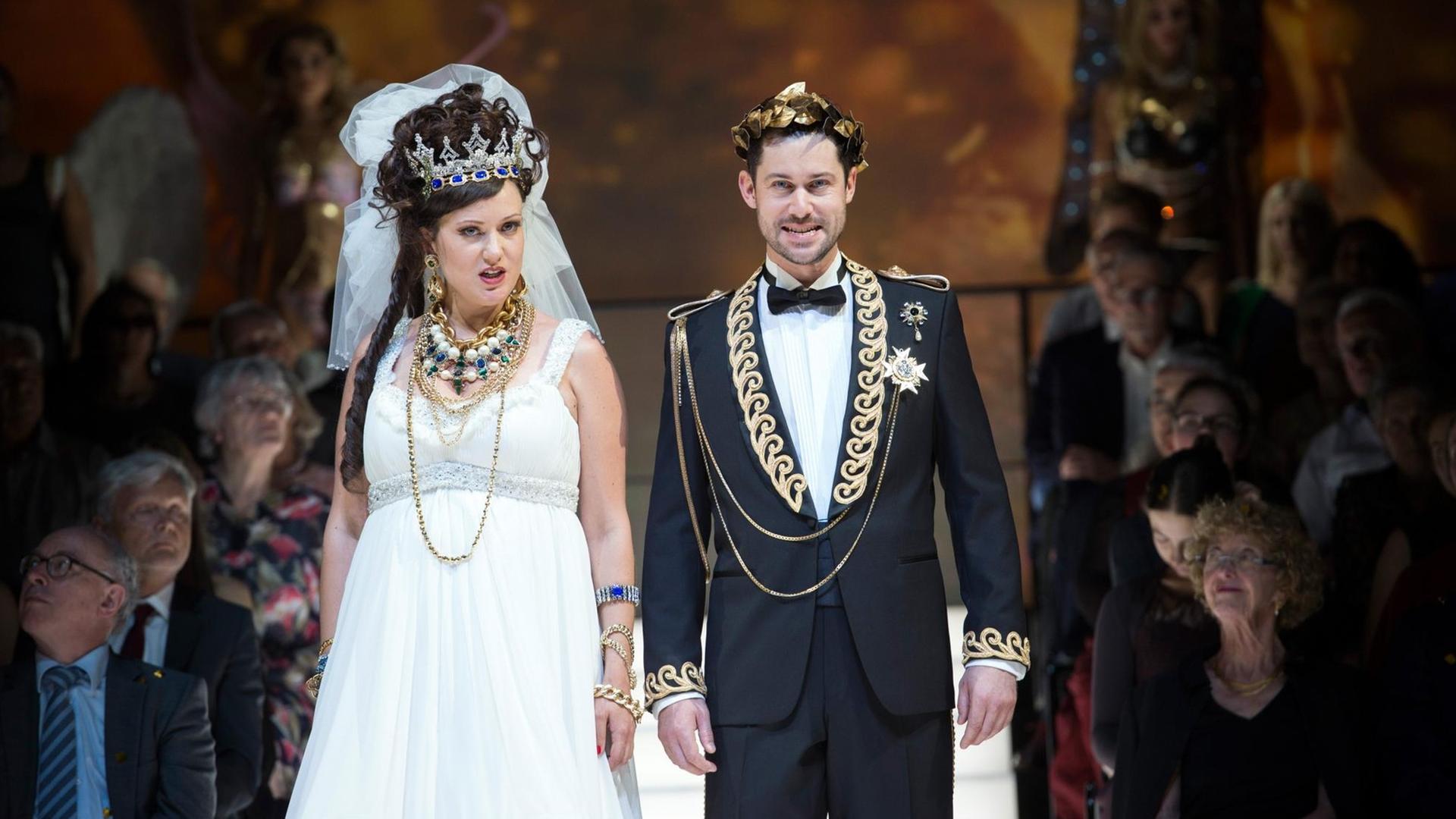 Poppea (gespielt von Julie Fuchs) und Nerone (dargestellt von David Hansen) stehen in der Bildmitte. Im Hintergrund ist ein Teil des einrahmenden Publikums zu sehen. Poppea (gespielt von Julie Fuchs) und Nerone (dargestellt von David Hansen) stehen in der Bildmitte. Im Hintergrund ist ein Teil des einrahmenden Publikums zu sehen.