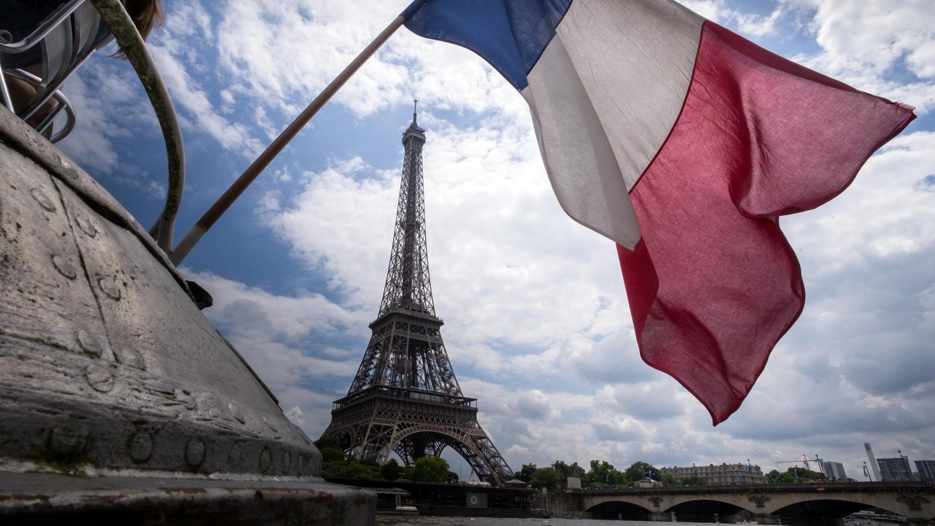 Eine französische Flagge weht vor dem Eiffelturm in Paris. Eine französische Flagge weht vor dem Eiffelturm in Paris.