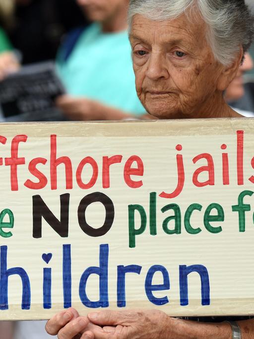 Eine ältere Frau demonstriert gegen die Unterbringung von Flüchtlingskindern auf der australischen Insel Nauru. "Offshore Jails are NO place for children", steht auf ihrem Plakat.