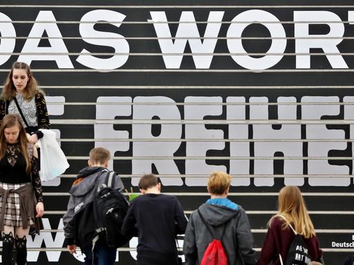Besucher gehen am 23.03.2017 über eine Treppe mit den Schriftzug "Für das Wort und die Freiheit" auf der Buchmesse in Leipzig.