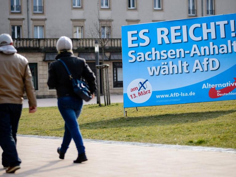 Zwei Menschen gehen in Merseburg in Sachsen-Anhalt an einem Wahlplakat der Alternative für Deutschland vorbei