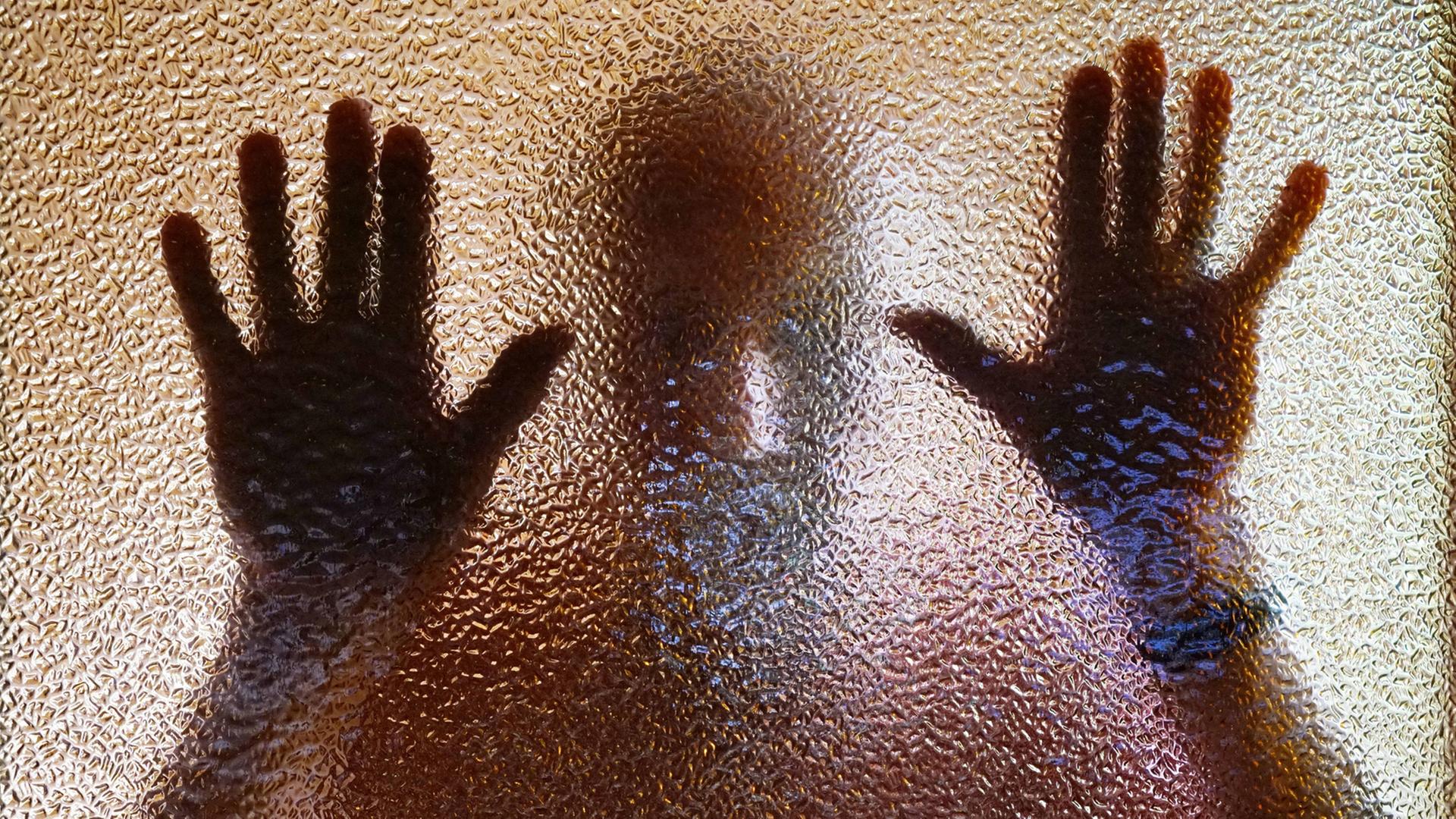 Ein Mann hinter einer nicht ganz transparenten Scheibe - die Hände am Glas Ein Mann hinter einer nicht ganz transparenten Scheibe - die Hände am Glas