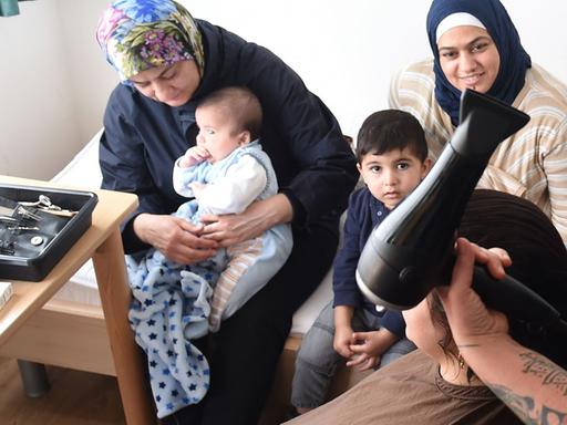 Friseurin Susanne Toraman schneidet am 28.09.2015 in Bremen einer Frau aus Syrien die Haare. Einmal die Woche schneidet Toraman Flüchtlingen in einem Übergangswohnheim kostenlos die Haare.
