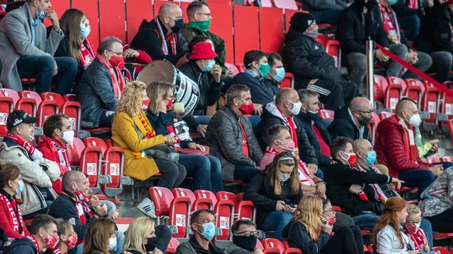 Fans von Union Berlin verfolgen das Spiel mit Abstand und Gesichtsmasken.