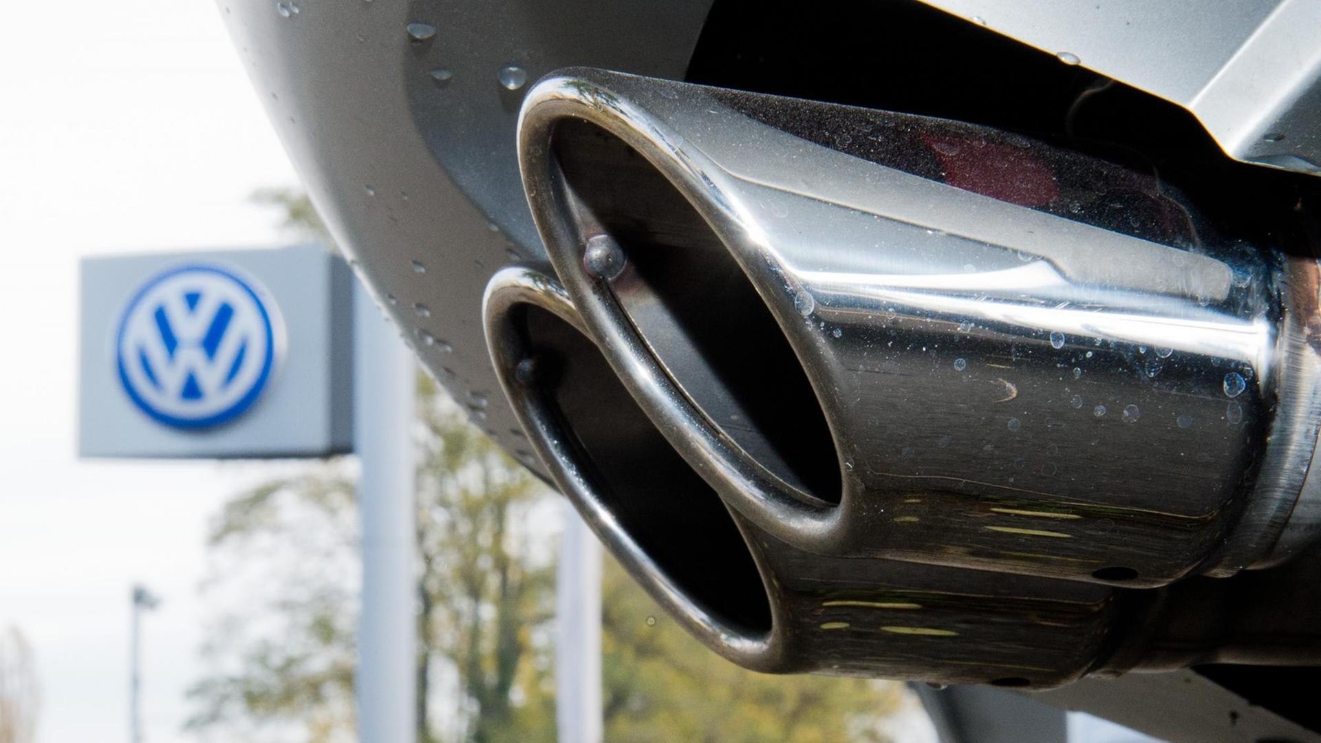 Ein Auspuff eines Autos mit einem VW-Logo im Hintergrund. Ein Auspuff eines Autos mit einem VW-Logo im Hintergrund.