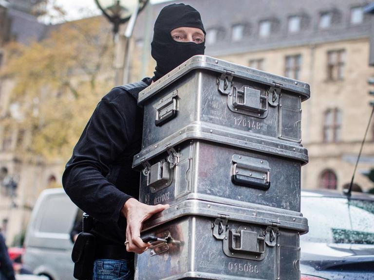 Beamte tragen Metallkisten in Räumlichkeiten eines Juweliers. Das Landeskriminalamt (LKA) Nordrhein-Westfalen und die Staatsanwaltschaft Düsseldorf sind gegen eine "international agierende kriminelle Vereinigung" vorgegangen. Die Beschuldigten sollen im großen Stil Bargeld aus Deutschland ins Ausland transferiert haben, wie das LKA Nordrhein-Westfalen mitteilte.