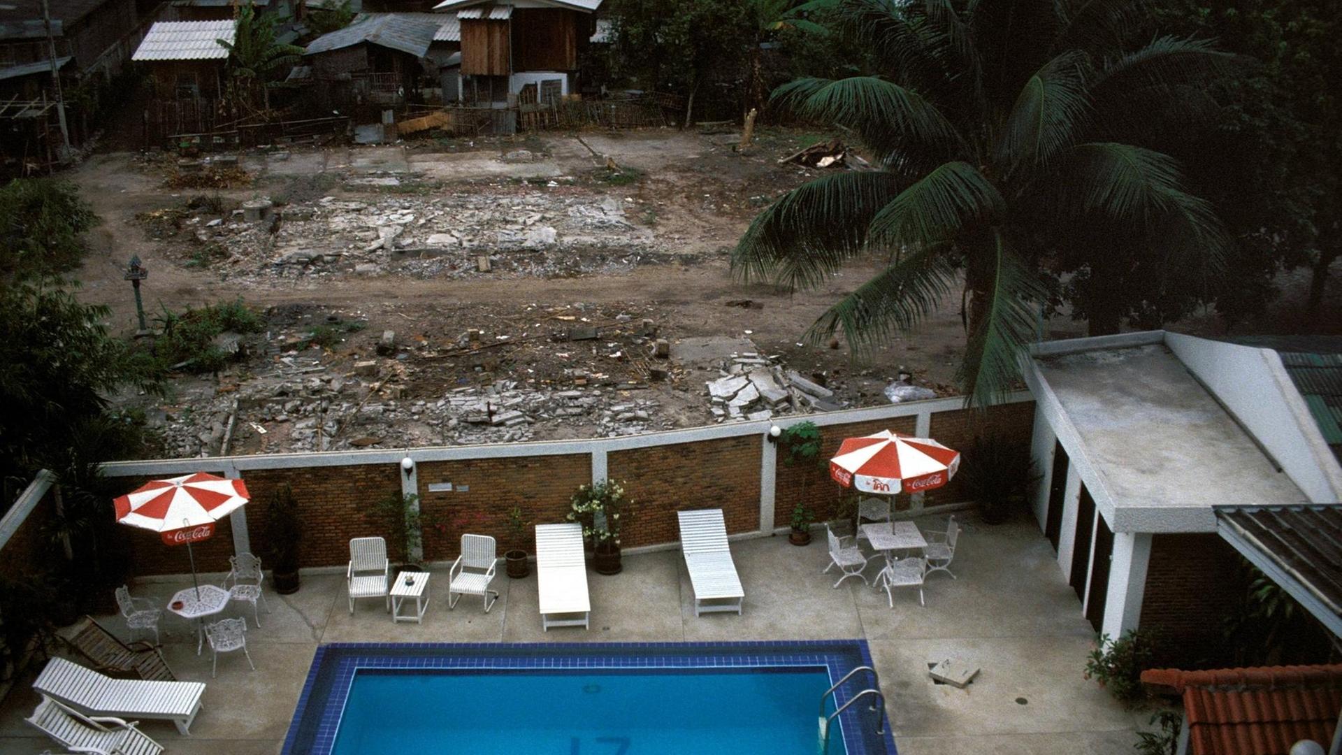 Blick auf den Poolbereich eines Hotels, der an ein thailändisches Armenviertel grenzt