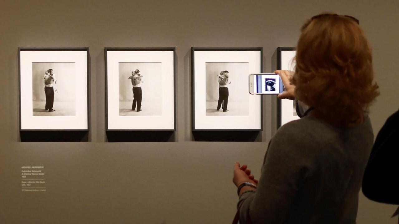 Eine Frau steht in einem Museum vor einem Bild und hält ein Handy davor. Eine Frau steht in einem Museum vor einem Bild und hält ein Handy davor.