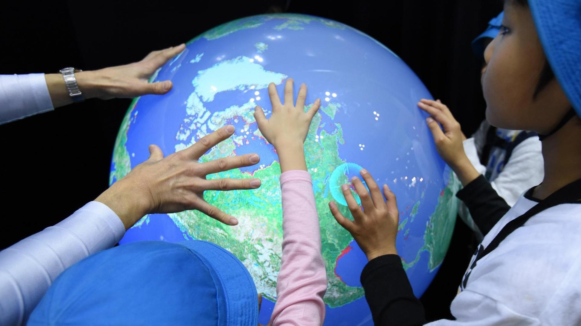 Japanische Schulkinder berühren bei einer Messe einen elektronischen Globus, der die Erhöhung des Meerwasserspiegels durch die Erderwärmung verdeutlicht. Japanische Schulkinder berühren bei einer Messe einen elektronischen Globus, der die Erhöhung des Meerwasserspiegels durch die Erderwärmung verdeutlicht.