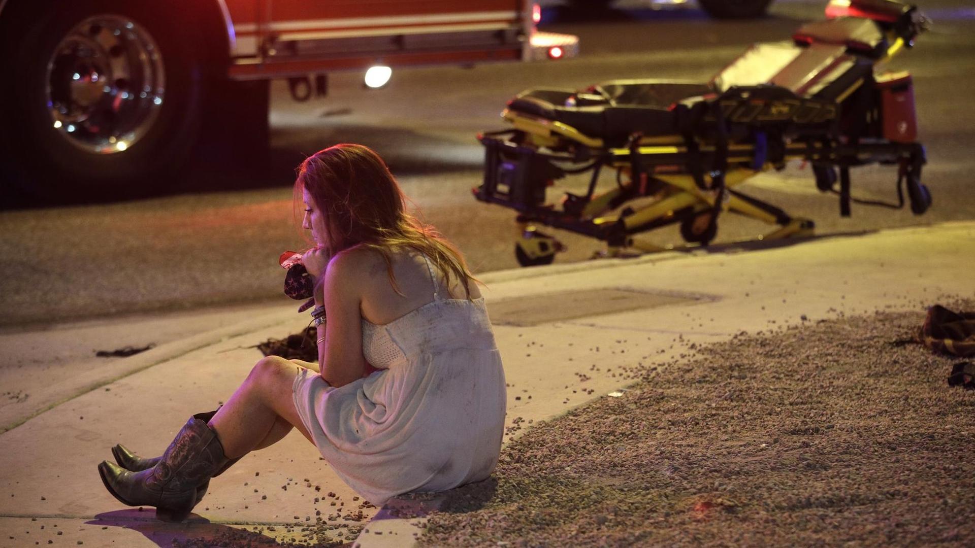 Eine Konzertbesucherin sitzt am 02.10.2017 in Las Vega (Nevada, USA) nahe des Mandalay Bay Resort und Casinos am Las Vegas Strip. In der US-Metropole Las Vegas sind nach Polizeiangaben mehr als 50 Menschen von Schüssen getötet worden. Eine Konzertbesucherin sitzt am 02.10.2017 in Las Vega (Nevada, USA) nahe des Mandalay Bay Resort und Casinos am Las Vegas Strip. In der US-Metropole Las Vegas sind nach Polizeiangaben mehr als 50 Menschen von Schüssen getötet worden.