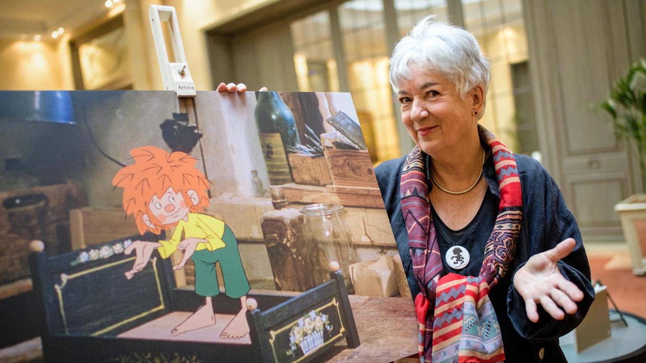 Barbara von Johnson, Illustratorin und Gestalterin des visuellen Erscheinungsbildes der Figur Pumuckl, steht neben einer Staffelei mit einer Pumuckl-Filmszene, aufgenommen am 26.2.2019 in München