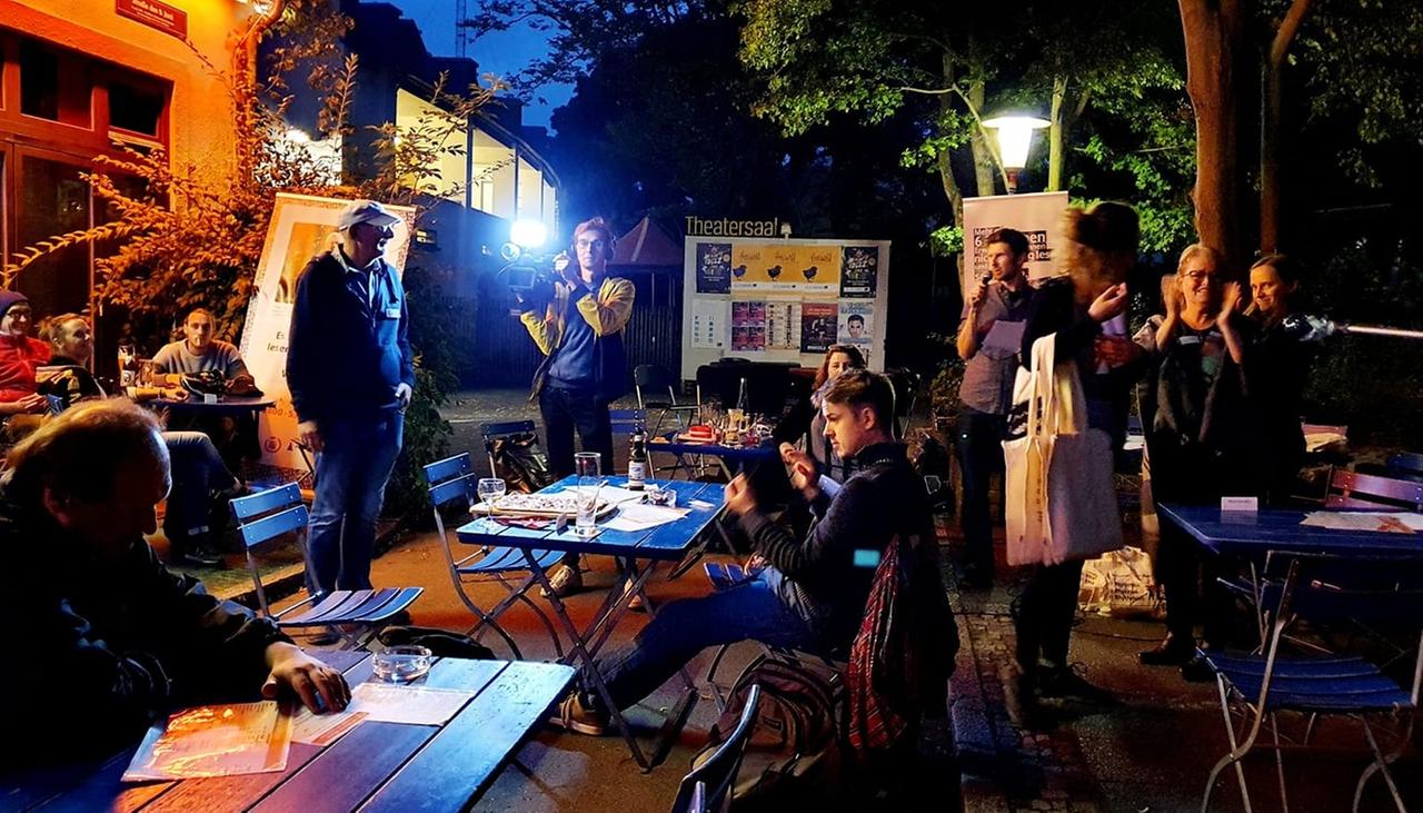 Menschen sitzen an Biertischen beim Pub-Quiz