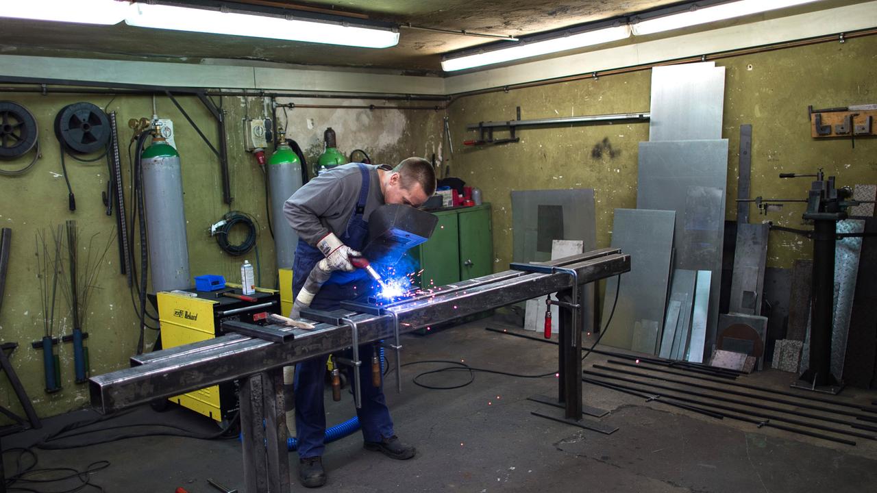 Ein Mann arbeitet mit einem Schweißgerät an einem Metallbalken.