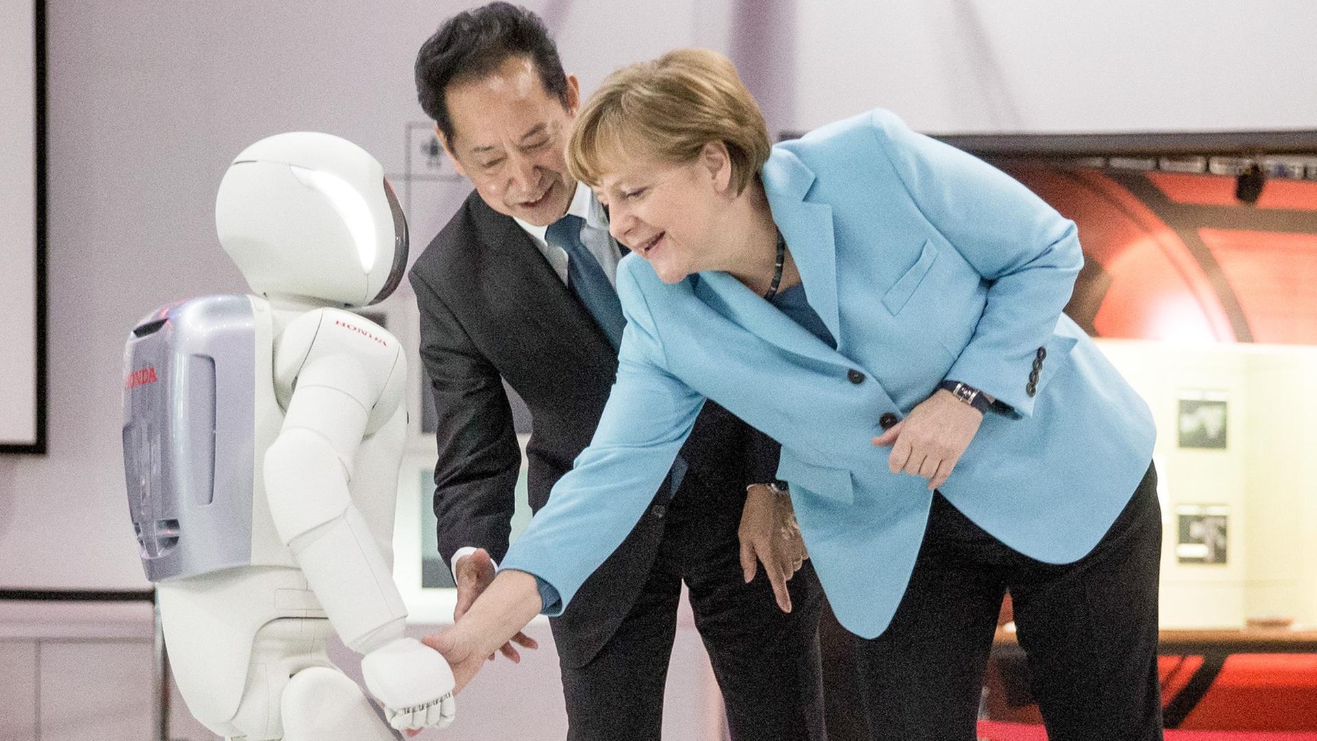 Bundeskanzlerin Angela Merkel (CDU) schaut sich am 09.03.2015 im Museum für Zukunftsorientierte Wissenschaft und Innovation Miraikan in Tokio in Japan den Roboter Asimo neben Museumsdirektor Mamoru Mohri an. Bundeskanzlerin Angela Merkel (CDU) schaut sich am 09.03.2015 im Museum für Zukunftsorientierte Wissenschaft und Innovation Miraikan in Tokio in Japan den Roboter Asimo neben Museumsdirektor Mamoru Mohri an.