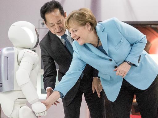 Bundeskanzlerin Angela Merkel (CDU) schaut sich am 09.03.2015 im Museum für Zukunftsorientierte Wissenschaft und Innovation Miraikan in Tokio in Japan den Roboter Asimo neben Museumsdirektor Mamoru Mohri an.