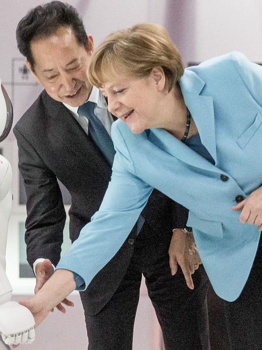 Bundeskanzlerin Angela Merkel (CDU) schaut sich am 09.03.2015 im Museum für Zukunftsorientierte Wissenschaft und Innovation Miraikan in Tokio in Japan den Roboter Asimo neben Museumsdirektor Mamoru Mohri an.