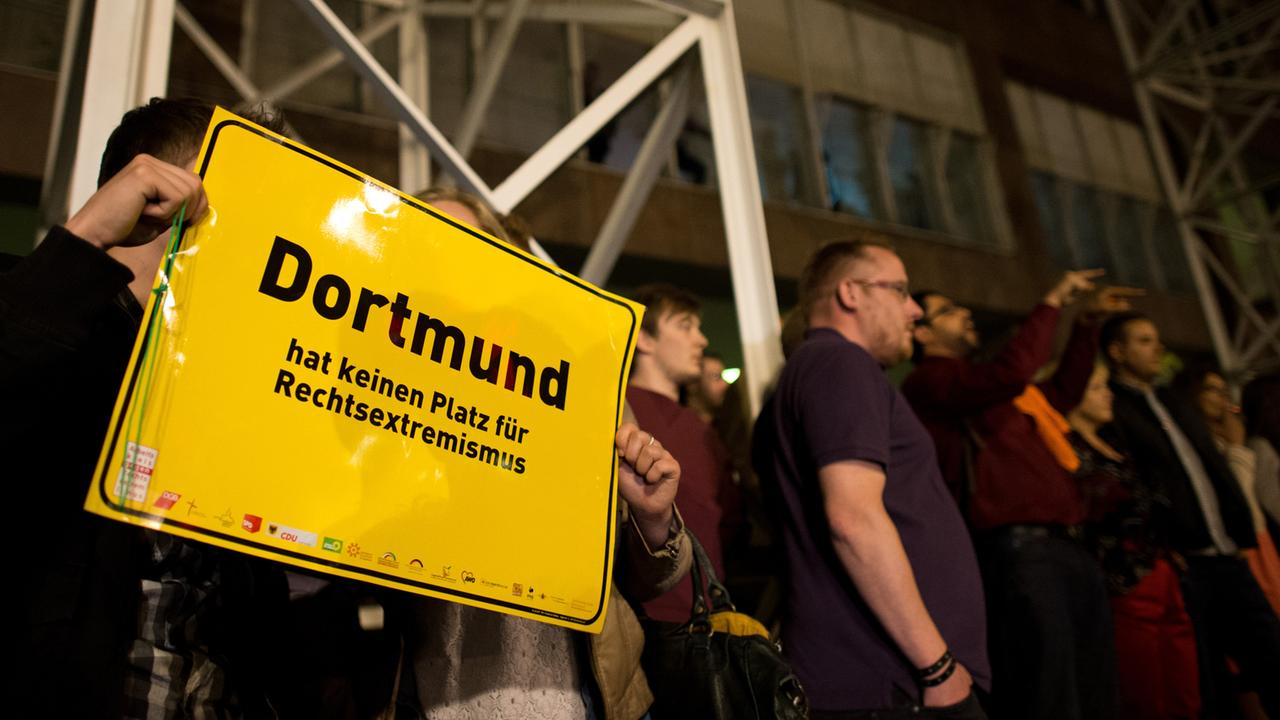 Ein Mann und eine Frau zeigen am 25.05.2014 vor dem Rathaus in Dortmund (Nordrhein-Westfalen) ein Schild mit der Aufschrift "Dortmund hat keinen Platz für Rechtsextremismus". Eine Gruppe von Männern aus dem rechten Umfeld hatten versucht, das Rathaus am Wahlabend zu stürmen, wurde daran aber von Bürgern gehindert. Ein Mann und eine Frau zeigen am 25.05.2014 vor dem Rathaus in Dortmund (Nordrhein-Westfalen) ein Schild mit der Aufschrift "Dortmund hat keinen Platz für Rechtsextremismus". Eine Gruppe von Männern aus dem rechten Umfeld hatten versucht, das Rathaus am Wahlabend zu stürmen, wurde daran aber von Bürgern gehindert.
