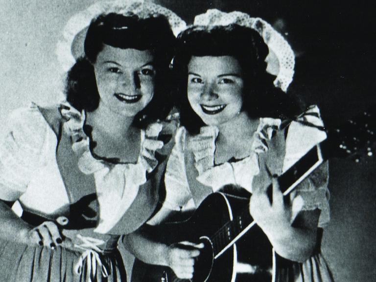 historische schwarz-weiß Fotografie mit den DeZurik Sisters in stilisierten Dirndln und mit einer Country-Gitarre