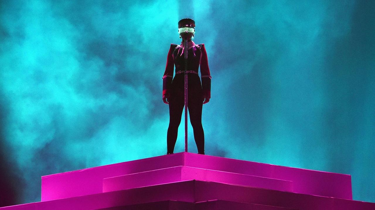 Janelle Monáe betritt bei einem Konzert auf dem Coachella-Festival die blau beleuchtete Bühne und trägt ein futuristisches Space-Kostüm mit einer geheimnisvoll schimmernden, grünen Science-Fiction-Brille. Janelle Monáe betritt bei einem Konzert auf dem Coachella-Festival die blau beleuchtete Bühne und trägt ein futuristisches Space-Kostüm mit einer geheimnisvoll schimmernden, grünen Science-Fiction-Brille.