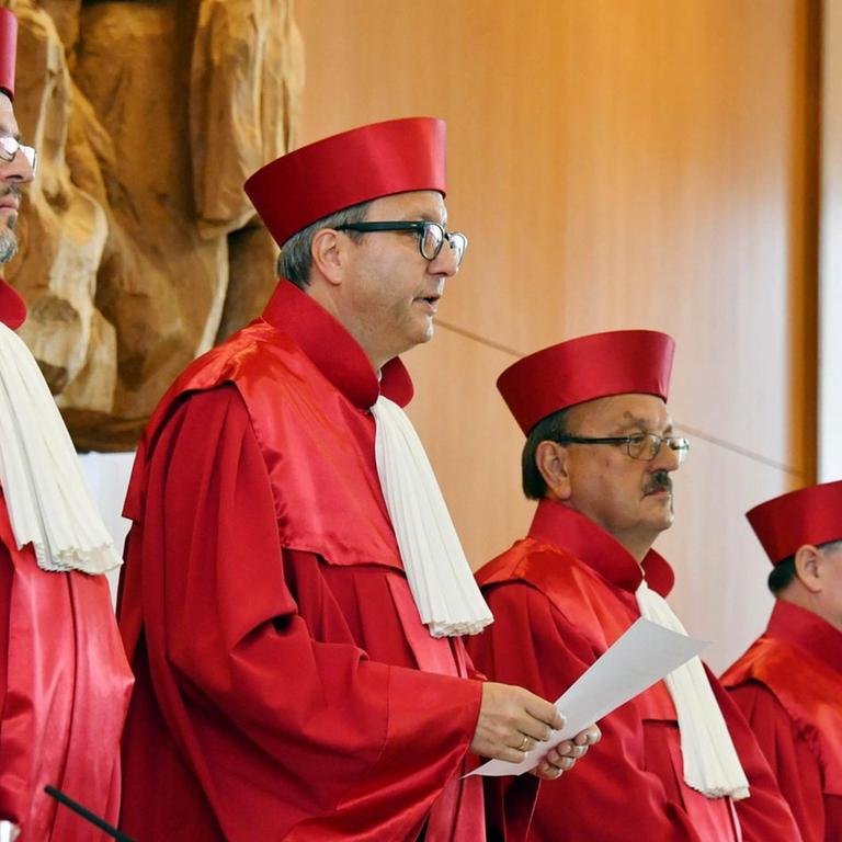 Das Bild zeigt die nebeneinander stehenden Richter in ihren roten Roben zu Beginn der Urteilsbegründung.