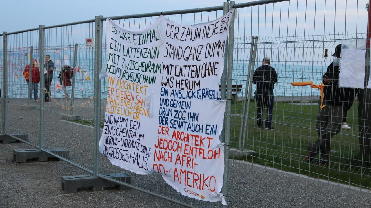 Der Grenzzaun zwischen Konstanz und Kreuzlingen. Am Zaun hängt ein Transparent mit einem mahnenden Gedicht.