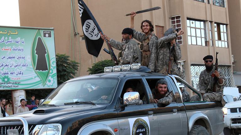 Angebliche Kämpfer der Terrorgruppe IS in der syrischen Stadt ar-Raqqa sitzen bewaffnet in und auf einem Auto. Angebliche Kämpfer der Terrorgruppe IS in der syrischen Stadt ar-Raqqa sitzen bewaffnet in und auf einem Auto.