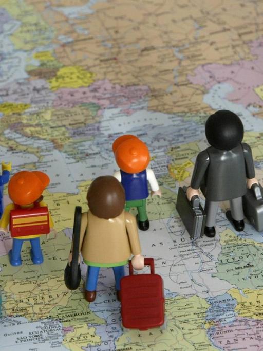Zuwanderung - Spielzeugfiguren mit Koffern unterwegs auf einer Landkarte von Süden nach Norden
